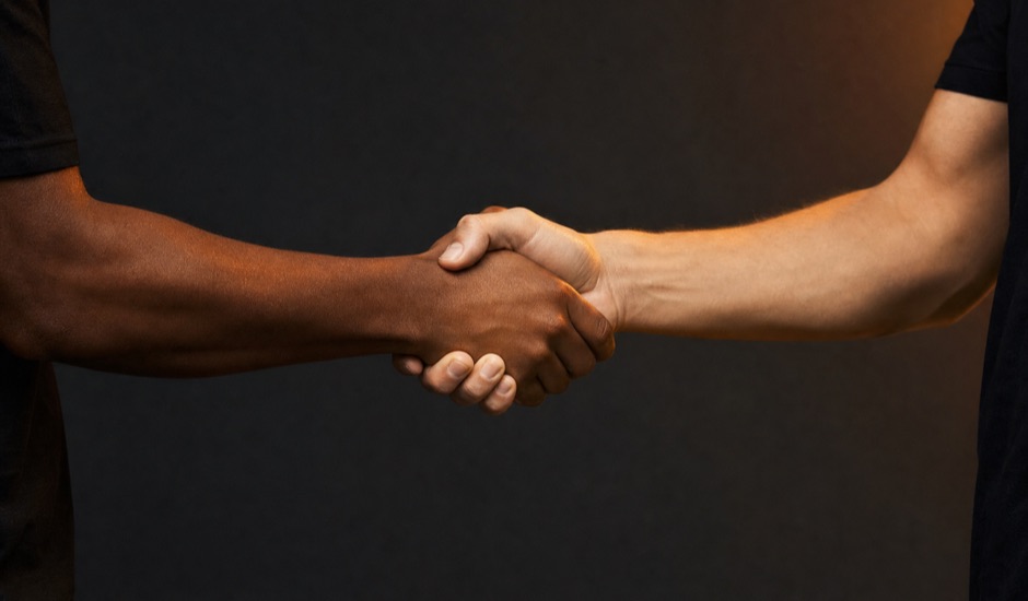 Close-up of a firm handshake under warm amber light: commitment and trust